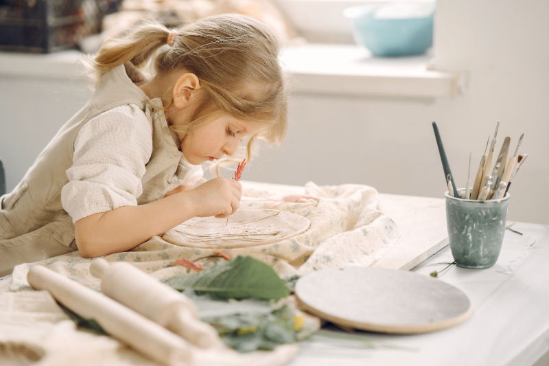 little-girl-makes-clay-plate-decorates-it